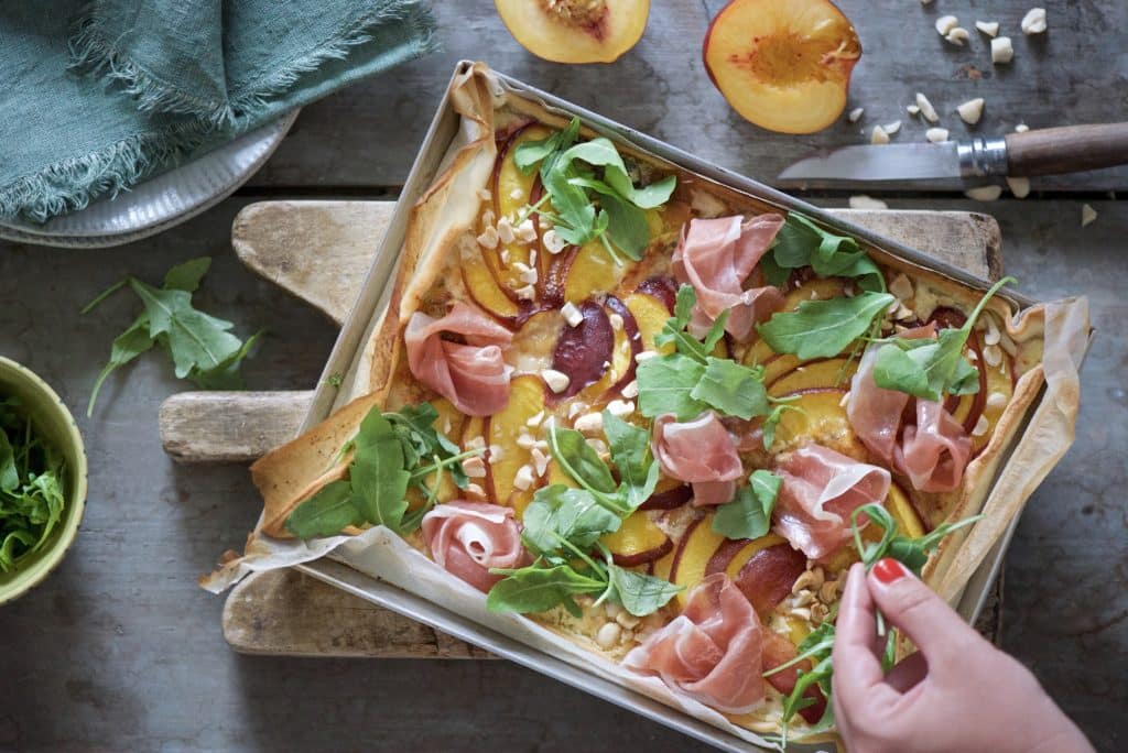 Flammenkuchen con pesche, prosciutto crudo e rucola